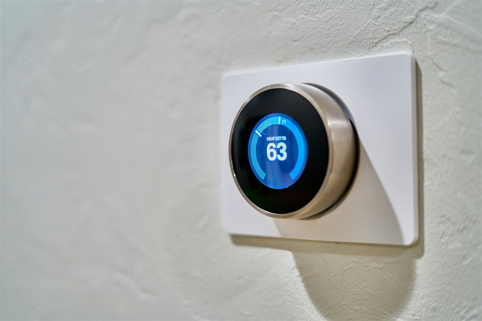 Ronde slimme thermostaat aan een lichte muur